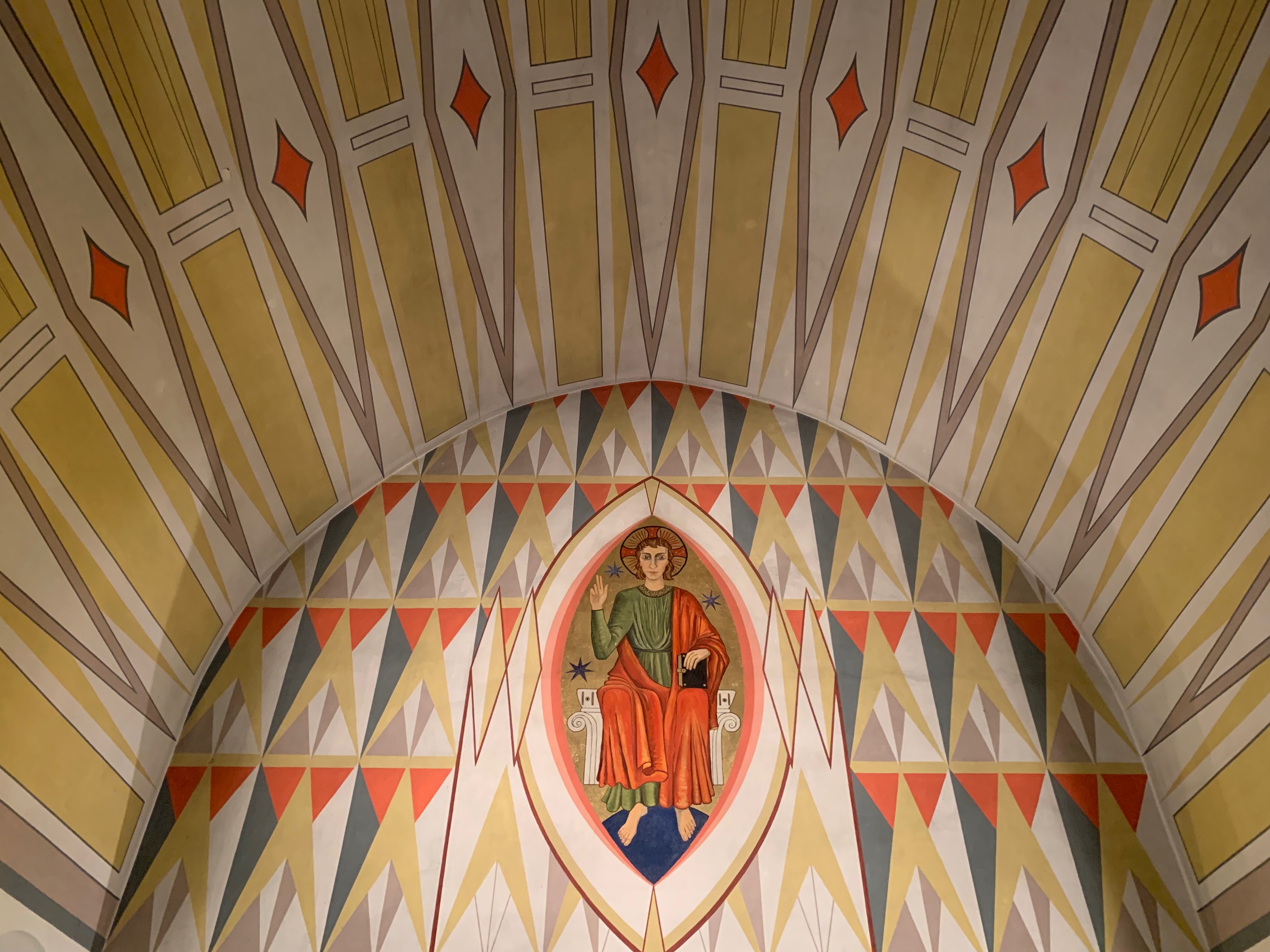 Seurakuntaa tervehtivä Jeesus Kristus kattomaalauksessa Vesisaaren kirkon alttarin yläpuolella.
