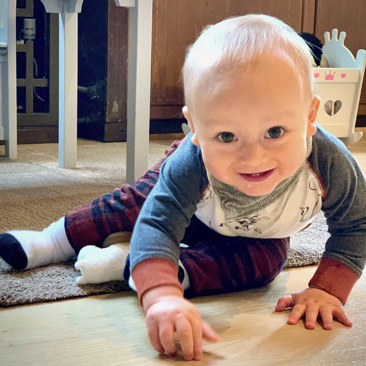 Vauva istuu ja hymyilee leikkiessään.