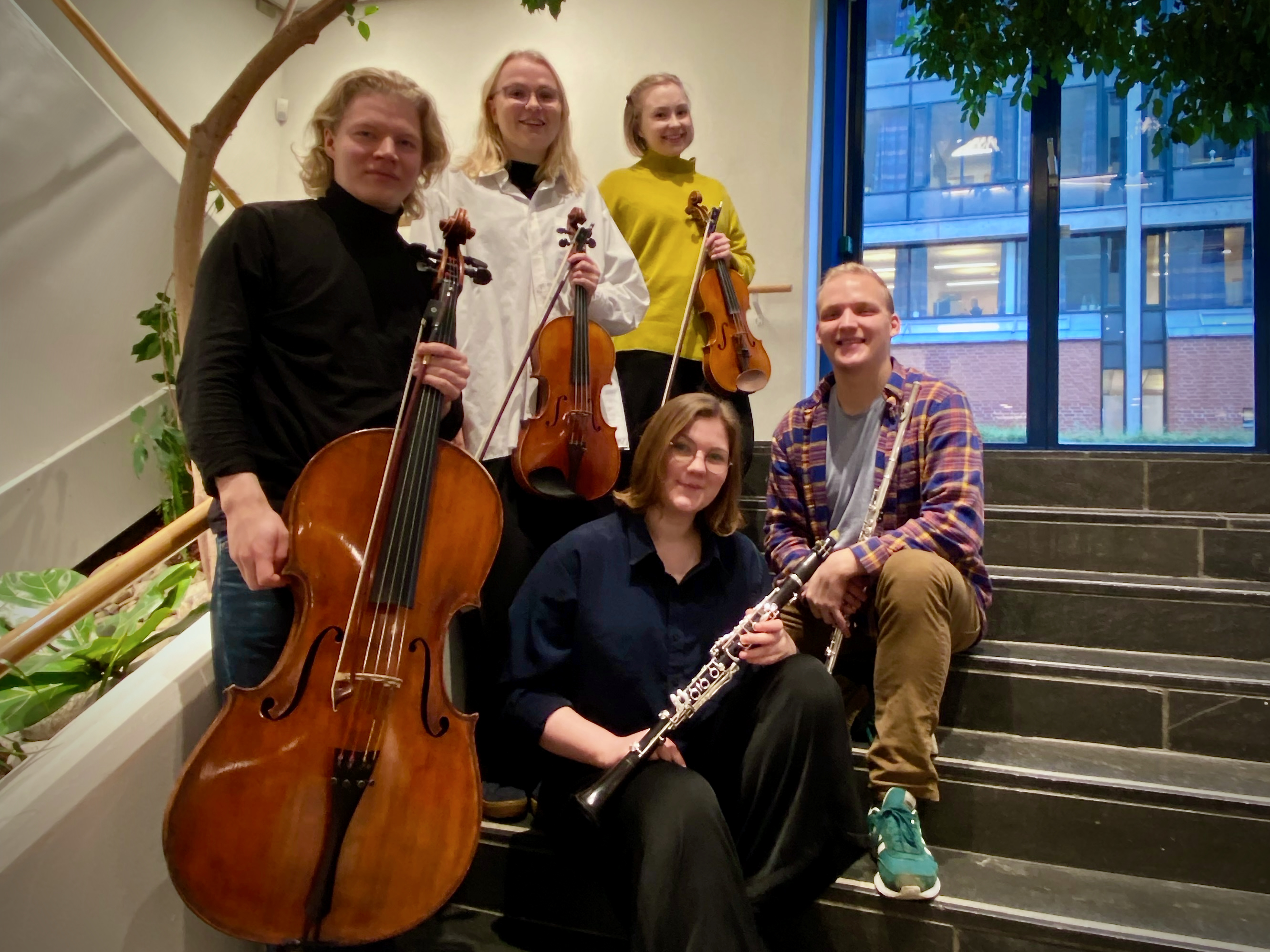 Viisi suomalaista musiikin opiskelijaa ryhmäkuvassa soittimiensa kanssa.